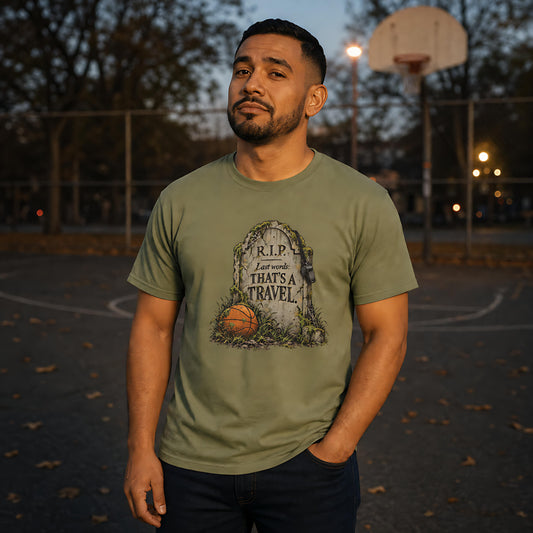Man wearing the Moss That's a Travel Tee on an outdoor basketball court at dusk, fallen leaves on the asphalt – Ref' Crew basketball referee Halloween tee