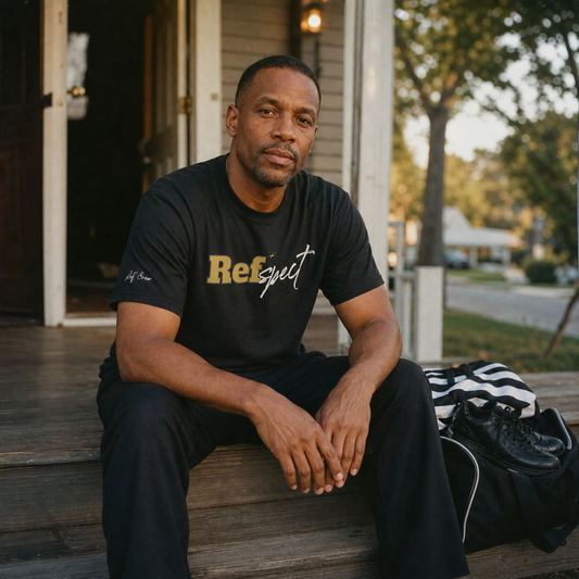 Basketball referee sitting on a porch step at golden hour wearing the black Refspect Tee, his striped officiating jersey and kit bag beside him – Ref' Crew
