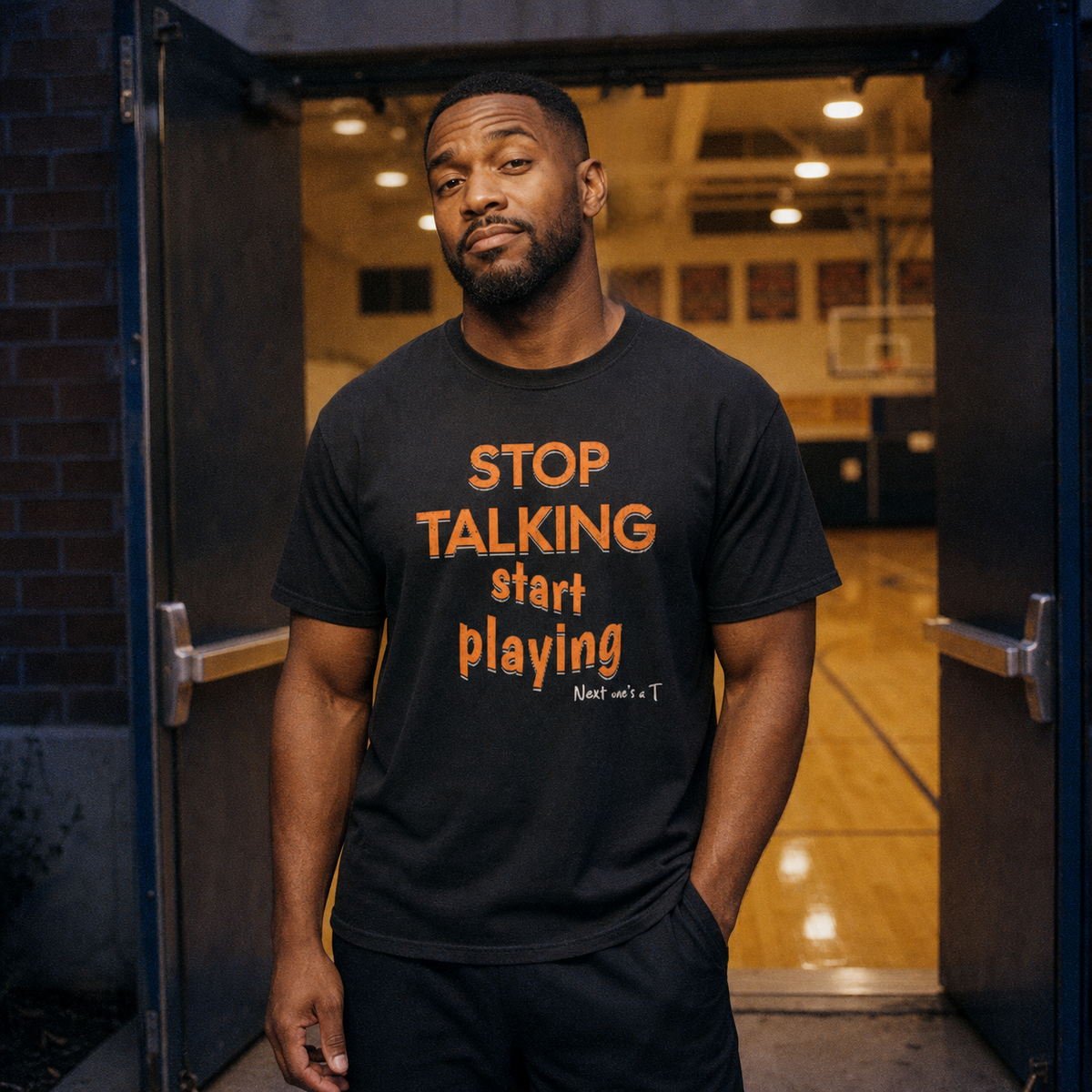 Man wearing the Black Stop Talking, Start Playing Tee in a gym doorway, orange "STOP TALKING start playing" lettering – Ref' Crew basketball referee tee