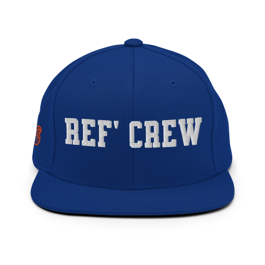 Royal blue Yupoong snapback with "REF' CREW" in white 3D puff print, orange whistle/basketball icon.