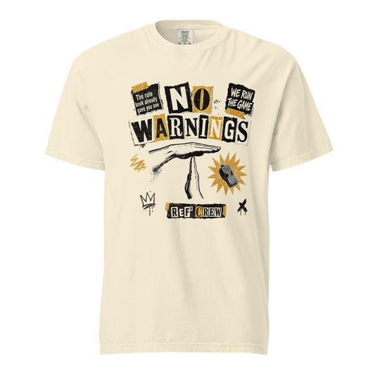 The No Warnings Tee in Ivory — front view. NO WARNINGS in torn ransom-note letters with the referee technical "T" signal and a Fox 40 whistle, on garment-dyed heavyweight cotton.