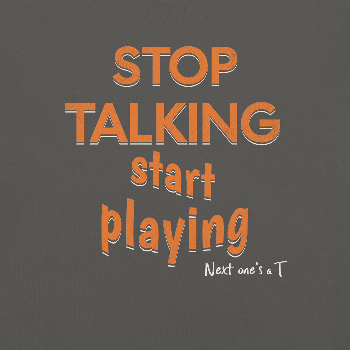 Close-up of the orange "STOP TALKING / start playing" print with white drop shadow and "Next one's a T" on Pepper garment-dyed heavyweight cotton